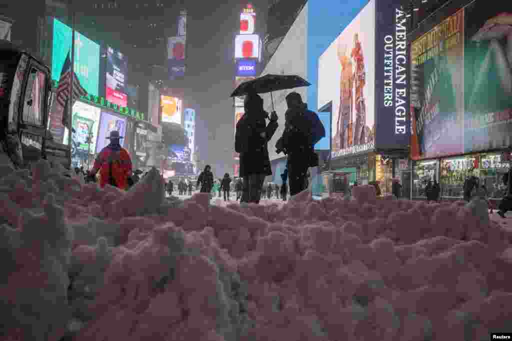 Люди стоят посреди неубранного снега на Таймс Сквер