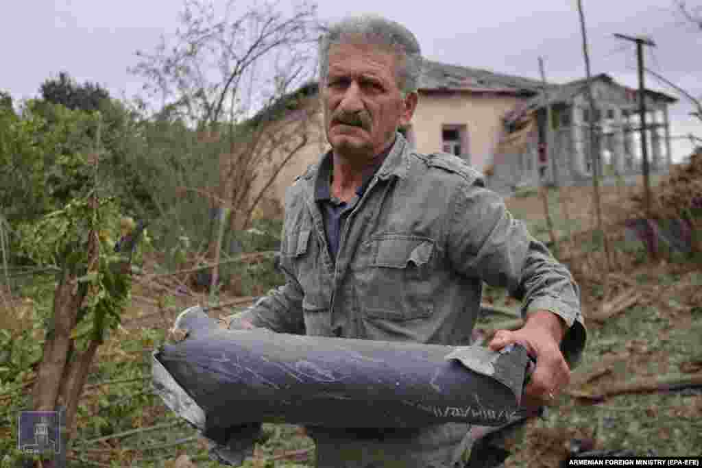 A man at an undisclosed location holds part of an artillery shell, fired during renewed fighting in September 2020 between Armenian, Karabakhi, and Azerbaijani forces over the Nagorno-Karabakh region. The photo was published by the Armenian Foreign Ministry. &nbsp;