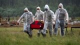 Virus Outbreak Russia -- file -- Cemetery workers wearing protective suits carry the coffin of a COVID-19 victim in the special purpose for coronavirus victims section of a cemetery in Kolpino, outside St.Petersburg, Russia, Tuesday, June 30, 2020. 