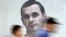 UKRAINE -- People walk past a poster with a photo of Ukrainian film director Oleg Sentsov, taken by journalist Anton Naumlyuk, and displayed in a shop window in the center of Kyiv on July 5, 2018.