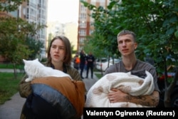 Жители Киев у своего многоквартирного дома, пострадавшего от удара российского беспилотника, 2 октября 2026 года. Фото Reuters