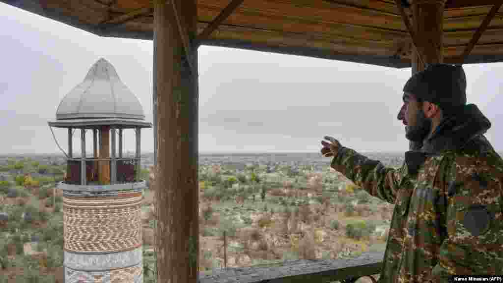 An Armenian man points toward a minaret at Agdam's 19th-century Juma mosque on November 19, 2020. The building, also known as the Agdam mosque, survived the 1992-1994 Karabakh war, but was abandoned during ethnic Armenians' occupation of the town. On November 20, 2020, Azerbaijanis attended Friday prayers in the sanctuary.&nbsp;