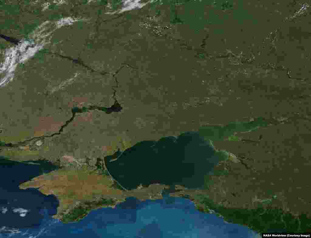 Дневные снимки спутников NASA показывают и другие важные последствия продолжающейся войны России против Украины.Снимки были сделаны 14 июня 2012 года и 6 июня 2026 года. На них видно обмеление Каховского водохранилища (в центре слева).Плотина Каховской ГЭС была разрушена 6 июня 2023 года, когда ее оккупировали российские военные. В результате вода из водохранилища затопила 46 городов и поселков, а также 1323 га земель в Херсонской области: на многих этих территориях почва больше непригодна для сельского хозяйства из-за того, что был смыт слой плодородной почвы. Из-за подрыва дамбы погибли 35 человек, еще 24 человека пропали без вести.  На фотографии 2026 года также видна полоса заброшенной земли, простирающаяся от центра изображения до правого верхнего угла, где проходит нынешняя линия соприкосновения ук