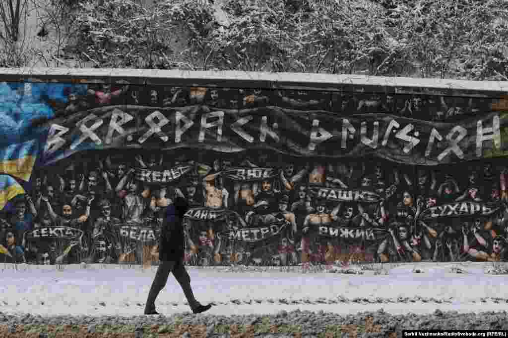 Этот мурал создан на основе фотографии, сделанной во время футбольного матча между "Динамо" Загреб и "Хайдук" Сплит в феврале 2023 года. Тогда хорватские футбольные болельщики почтили память украинских военных – футбольных болельщиков, погибших в боях с российскими военными. Фанаты подняли на трибунах баннеры с именами погибших и скандировали "Слава Украине!"