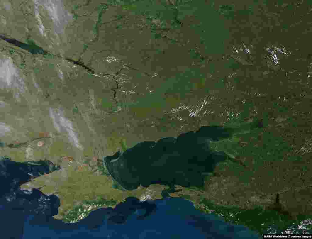 Дневные снимки спутников NASA показывают и другие важные последствия продолжающейся войны России против Украины.Снимки были сделаны 14 июня 2012 года и 6 июня 2026 года. На них видно обмеление Каховского водохранилища (в центре слева).Плотина Каховской ГЭС была разрушена 6 июня 2023 года, когда ее оккупировали российские военные. В результате вода из водохранилища затопила 46 городов и поселков, а также 1323 га земель в Херсонской области: на многих этих территориях почва больше непригодна для сельского хозяйства из-за того, что был смыт слой плодородной почвы. Из-за подрыва дамбы погибли 35 человек, еще 24 человека пропали без вести.  На фотографии 2026 года также видна полоса заброшенной земли, простирающаяся от центра изображения до правого верхнего угла, где проходит нынешняя линия соприкосновения ук