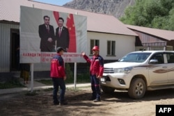 Рабочие компании Talco Gold, совместного таджикско-китайского добывающего предприятия, на фоне билборда с изображением лидера Китая Си Цзиньпина и президента Таджикистана Эмомали Рахмона