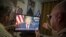 U.S. -- Miguel Saavedra (L) and his friend Oswaldo Hernandez watch U.S. President Donald Trump on TV, from their home in Miami, Florida, January 8, 2019