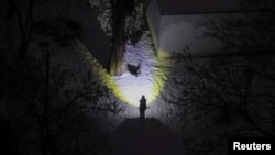 Житель Киева выгуливает собаку при свете фонарика во время блэкаута из-за ракетного удара армии РФ. 20 января 2026 года