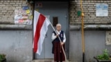 BELARUS -- Nina Bahinskaya, 73, poses for a photo holding an old Belarusian national flag at an entrance of her apartment building in Minsk, September 10, 2020